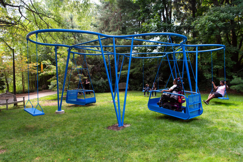 People swing on Cloud Swing at Grounds for Sculpture, including a wheelchair user